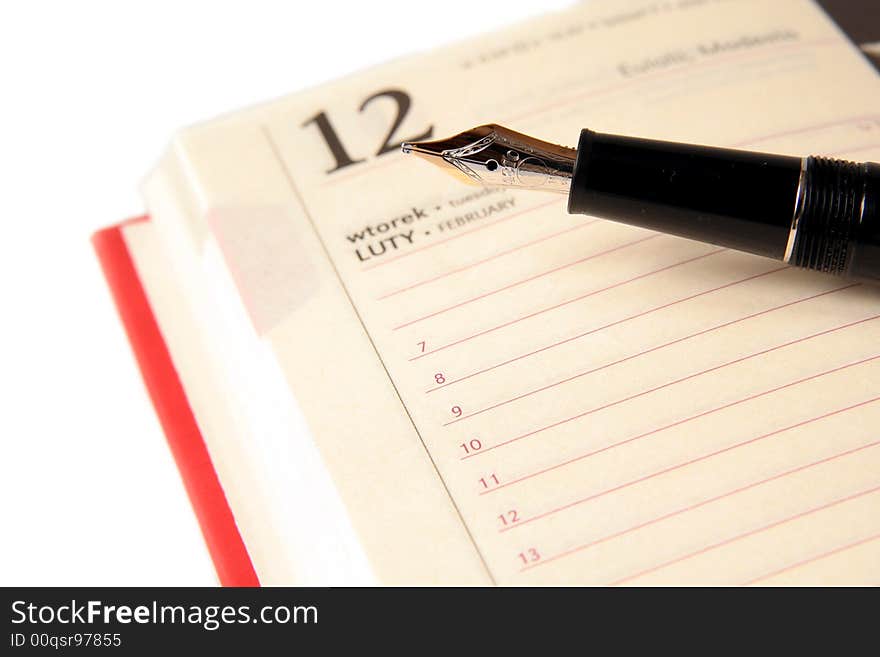 Gold and  black fountain pen on the opened diary on a light background. Gold and  black fountain pen on the opened diary on a light background