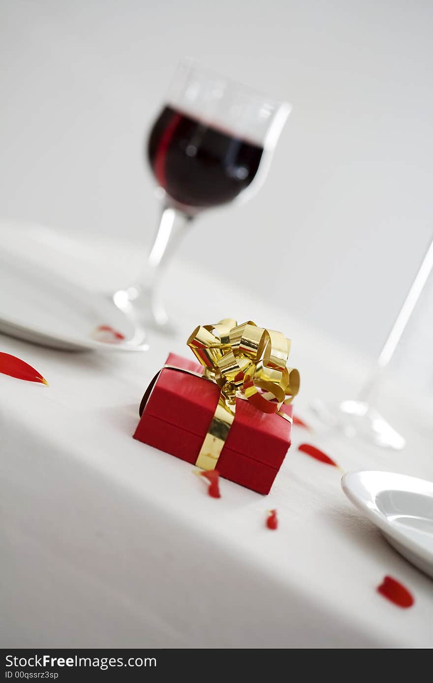 Gift lying on dinner table, some petals on the table cloth