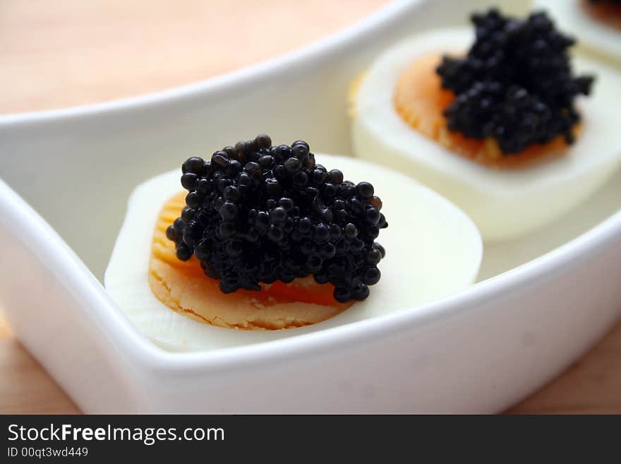 Closeup of a boiled egg with black caviar topping. Closeup of a boiled egg with black caviar topping.