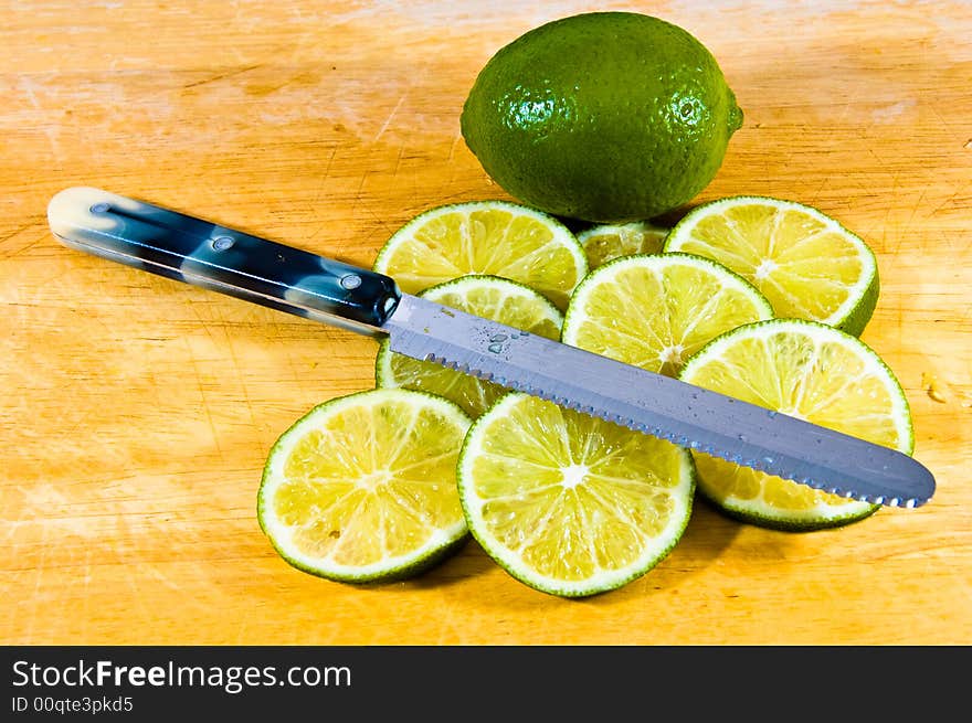 Limes sliced on a board with a knife. Limes sliced on a board with a knife