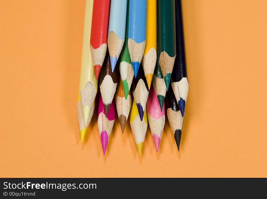 Stack of color pencils on orange background.