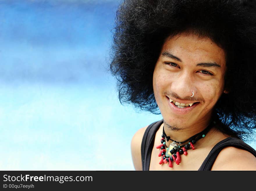 Portrait of a young Thai man with an afro isolated on blue.