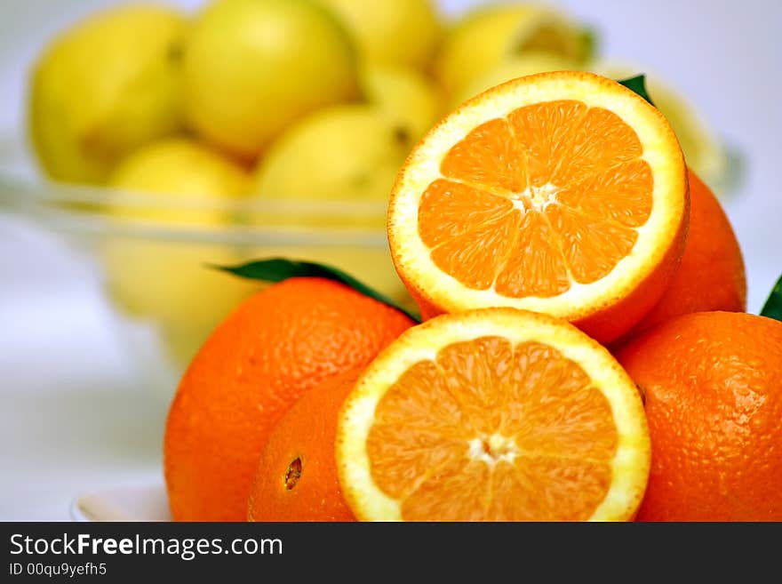 A pile of oranges with two slices and lemons in the background. A pile of oranges with two slices and lemons in the background.