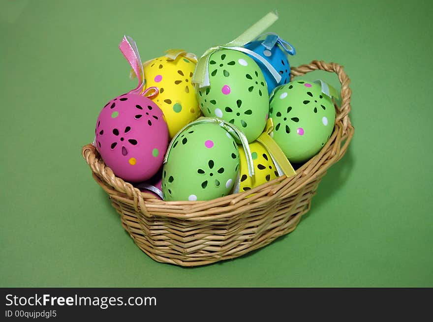 Closeup of colorful, beautifully crafted easter eggs in a wicker basket on a green background