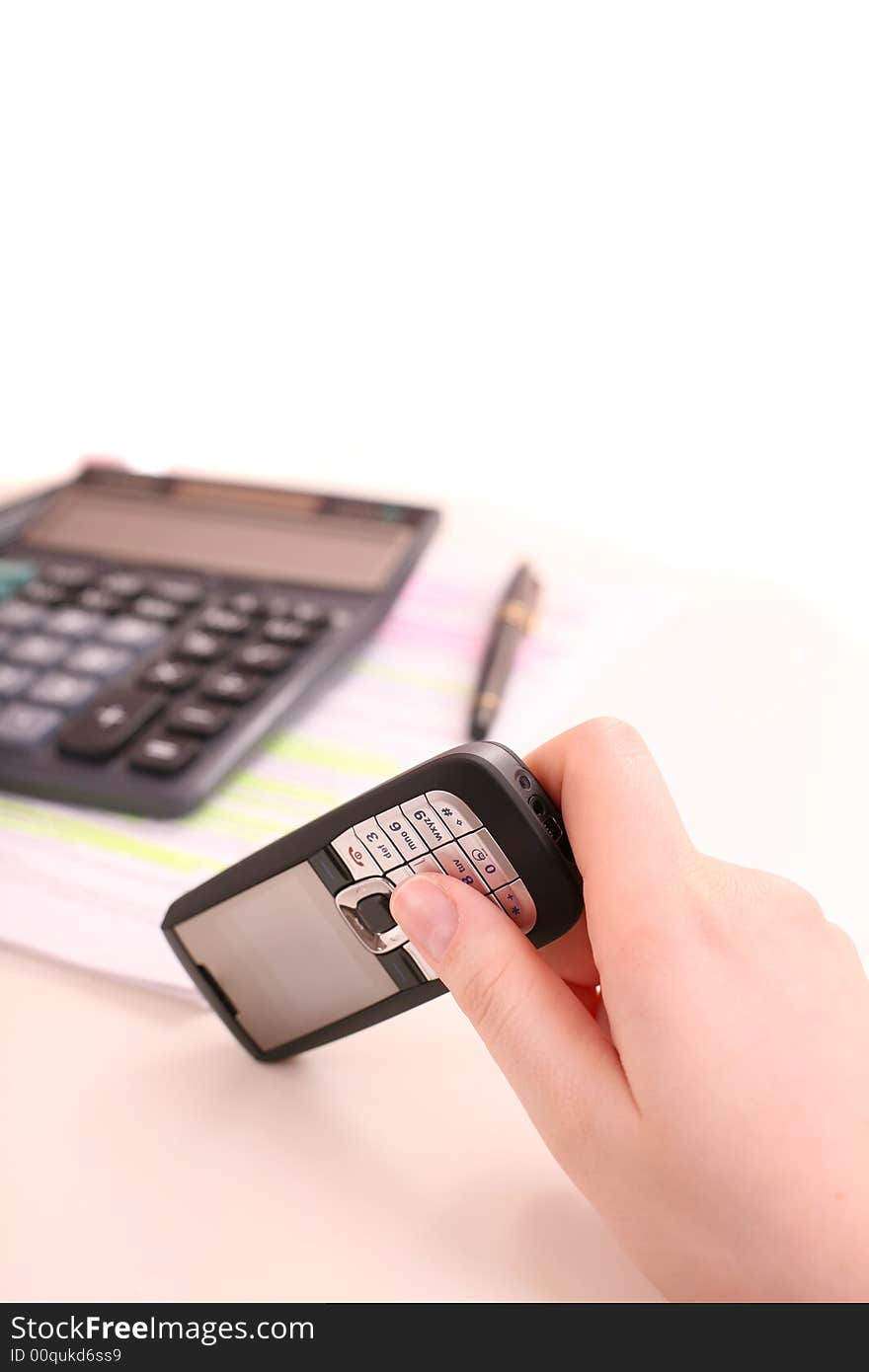 Cell phone in the female hand under the desk. Cell phone in the female hand under the desk