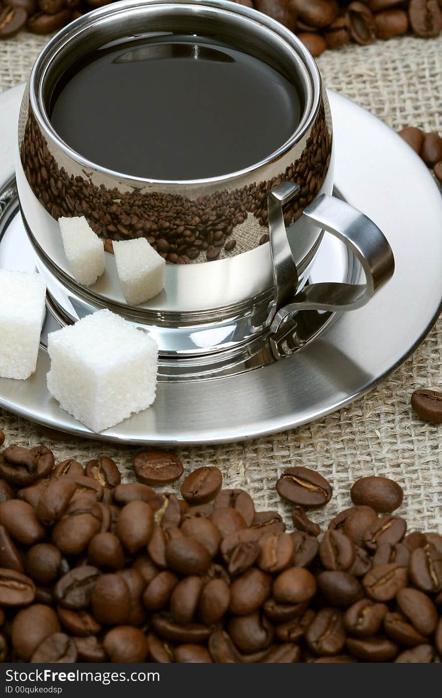 Cup of coffee with lump sugar and beans