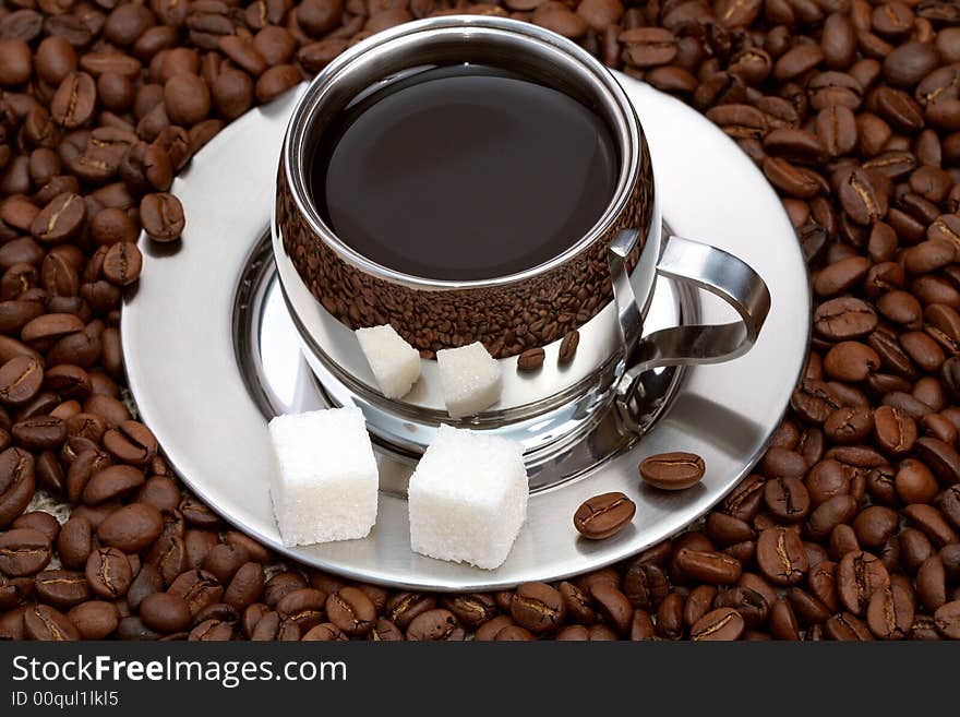 Cup of coffee with lump sugar and beans