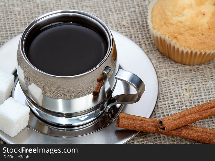 Cup of black coffee with muffin and cinnamon