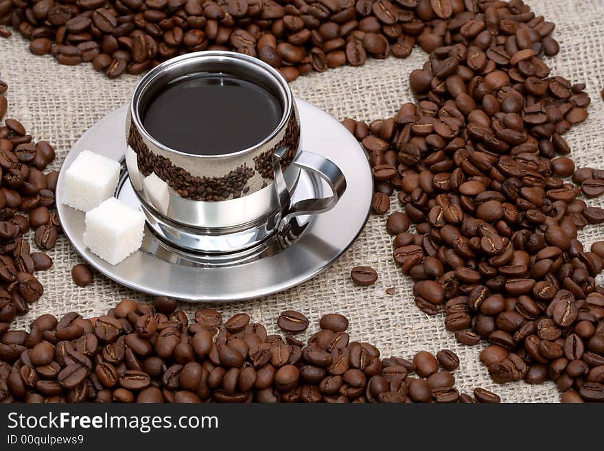 Cup of coffee with lump sugar and beans