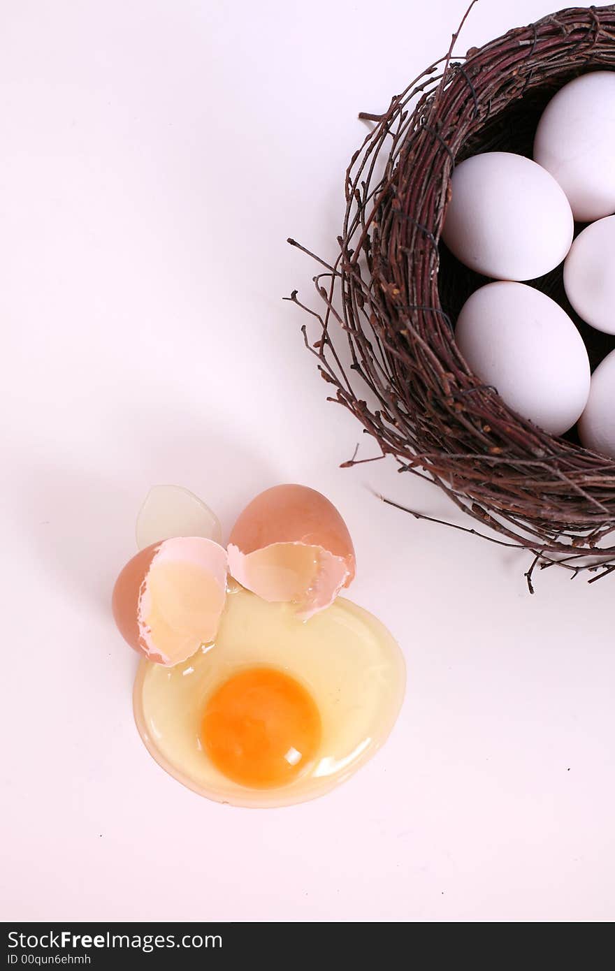 White eggs in the nest, brown broken egg next to nest