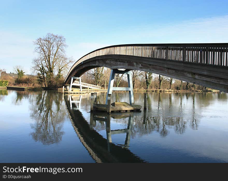 A contemporary Wooden Footbridge over the River Thames in England against a Blue Winter Sky