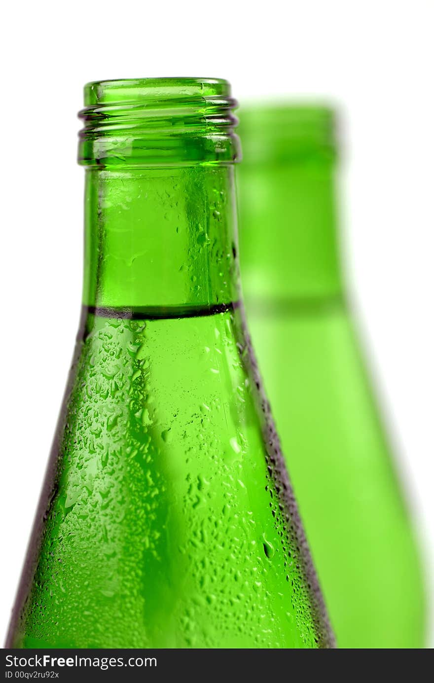 Bottled water in green, condensation-covered bottles; differential focus