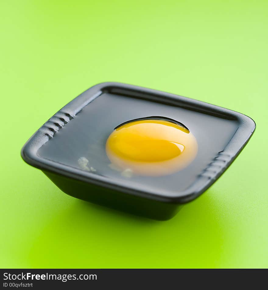 Egg on the black cup over a green table. Egg on the black cup over a green table