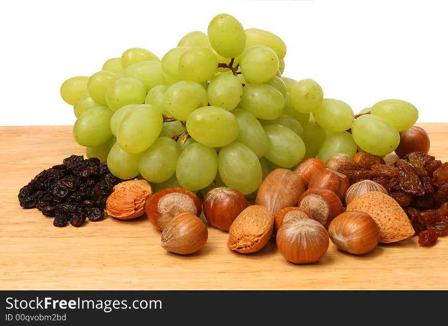 Fruit and nuts on wooden board against white