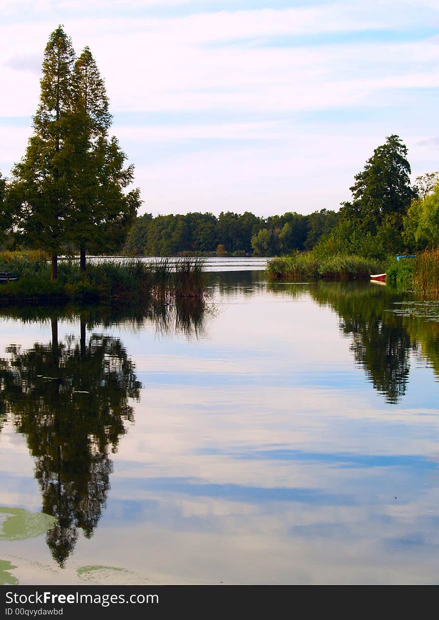 Landscape with reflecting trees and a little red boat