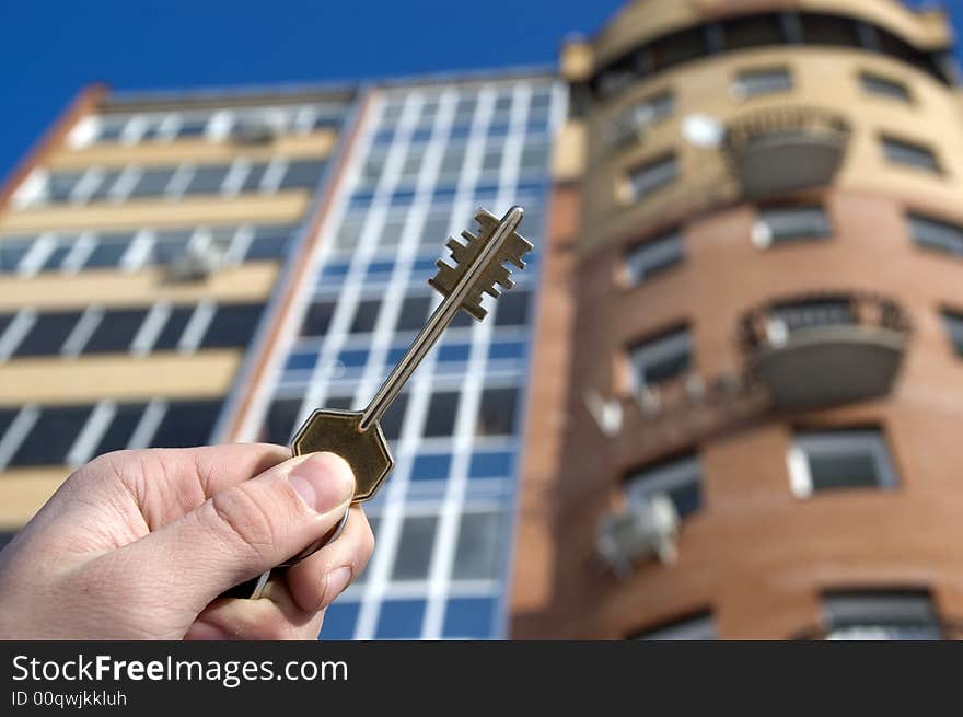 On a background of a modern brick house, hand with keys from an apartment. On a background of a modern brick house, hand with keys from an apartment.