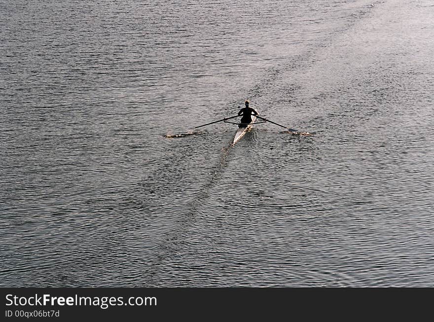 A lone rower on a river early in the morning