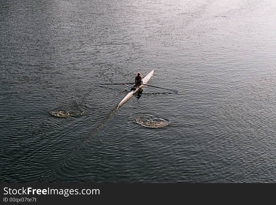 A lone rower on a river early in the morning