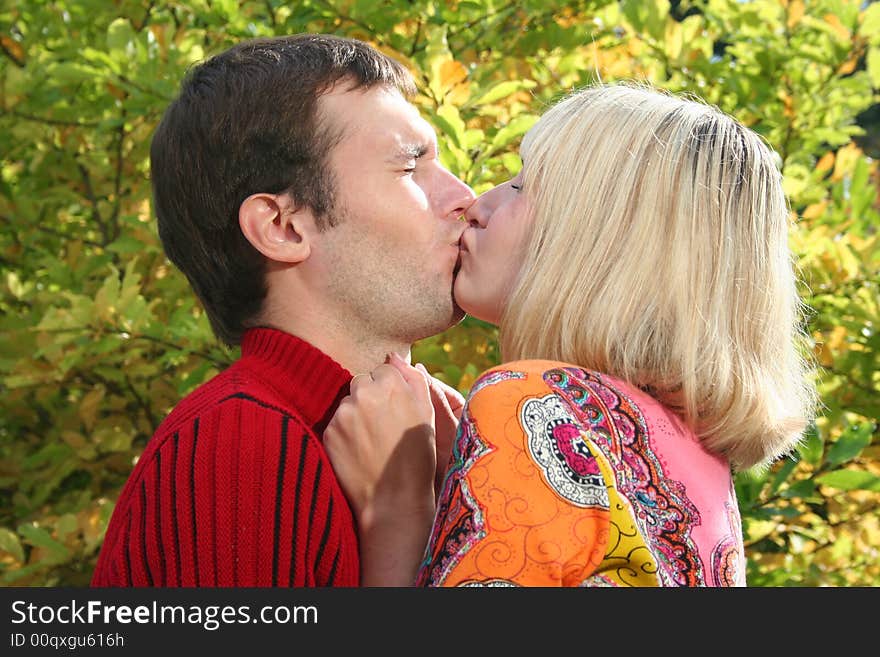 Beautiful couple is kissing near the autumn three