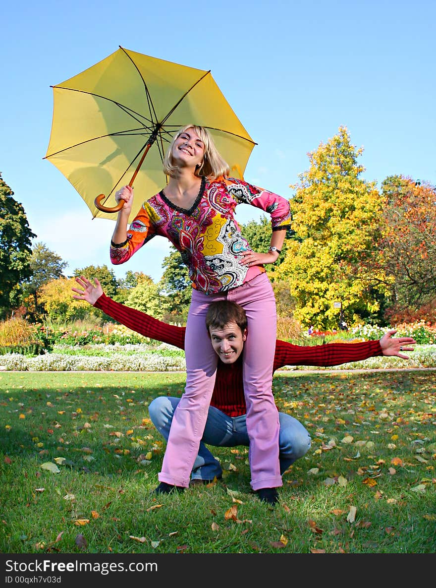 Young beautiful couple have fun under yellow umbrella. Young beautiful couple have fun under yellow umbrella