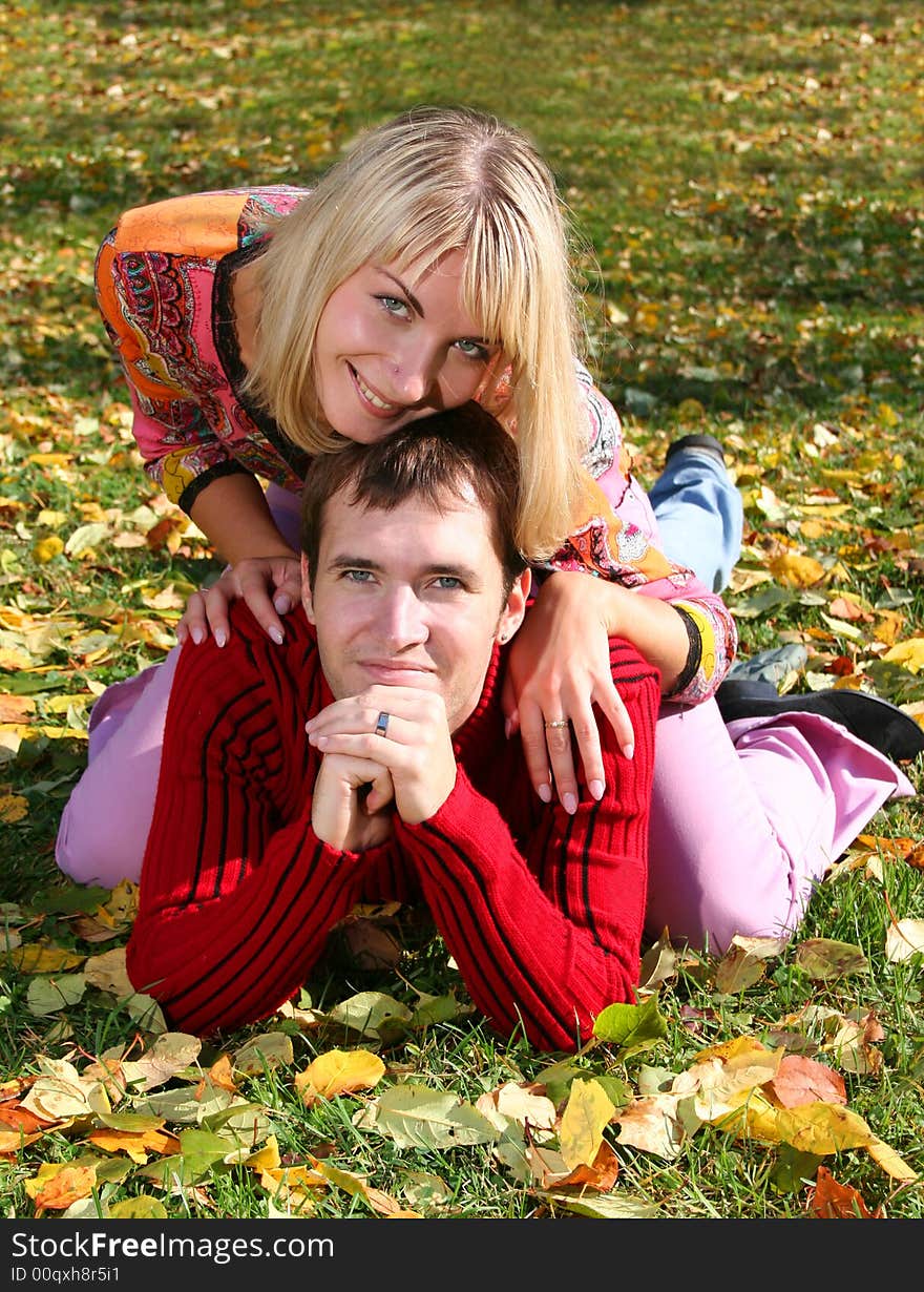 Young beautiful couple is laying on the autumn grass