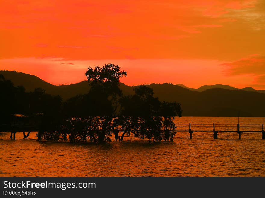 Orange sunset with silhouettes of mountain, trees and  bridge. Orange sunset with silhouettes of mountain, trees and  bridge