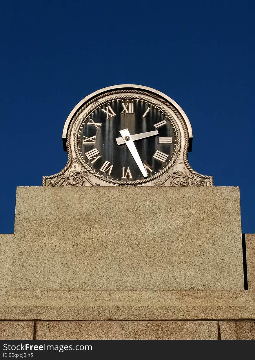 Old black faced clock with blue sky