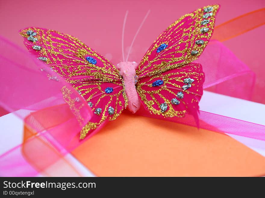 Pink butterfly on a white gift box as a decoration. Pink butterfly on a white gift box as a decoration