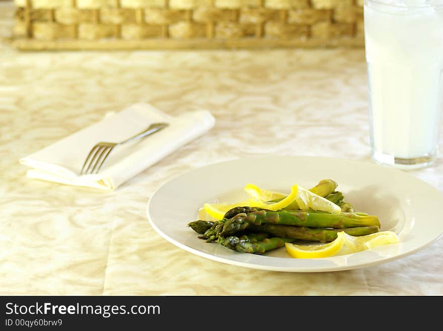 Asparagus stalks on white plate with lemon twists.