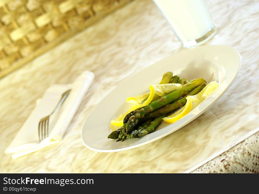 Asparagus stalks on white plate with lemon twists.