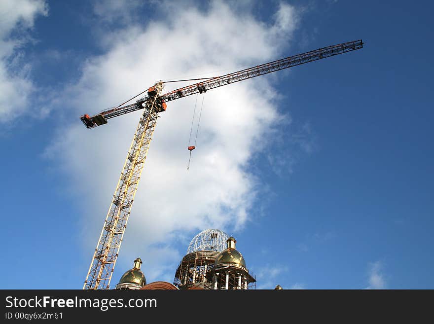 Tall crane and construction in cloudy blue sky