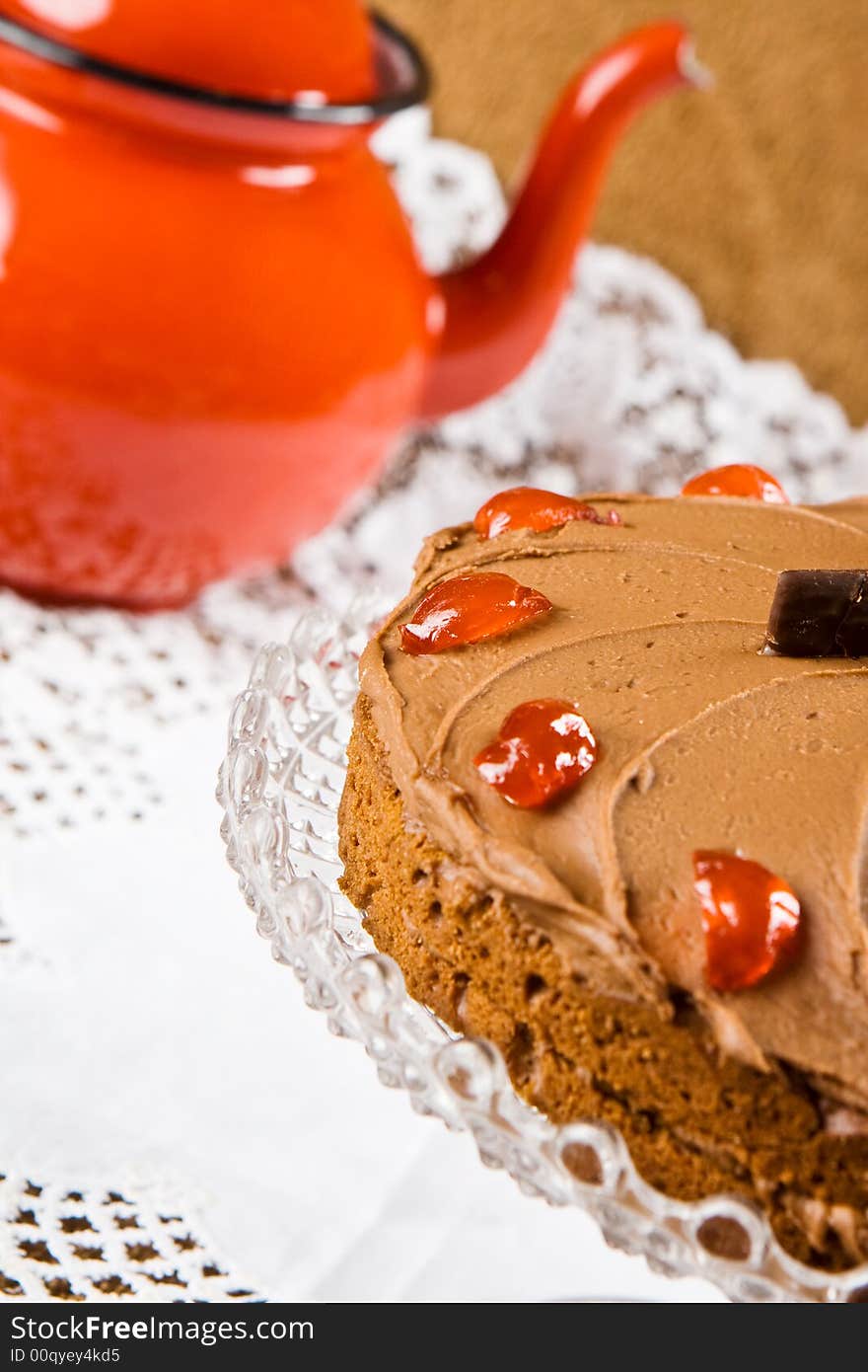 Freshly baked chocolate cake with a red tea pot in the background