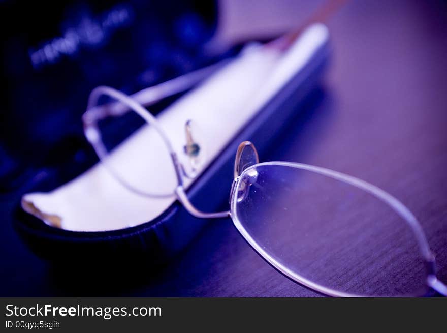 A closeup view of eyeglasses laying on a table or desk.  Color modified. A closeup view of eyeglasses laying on a table or desk.  Color modified
