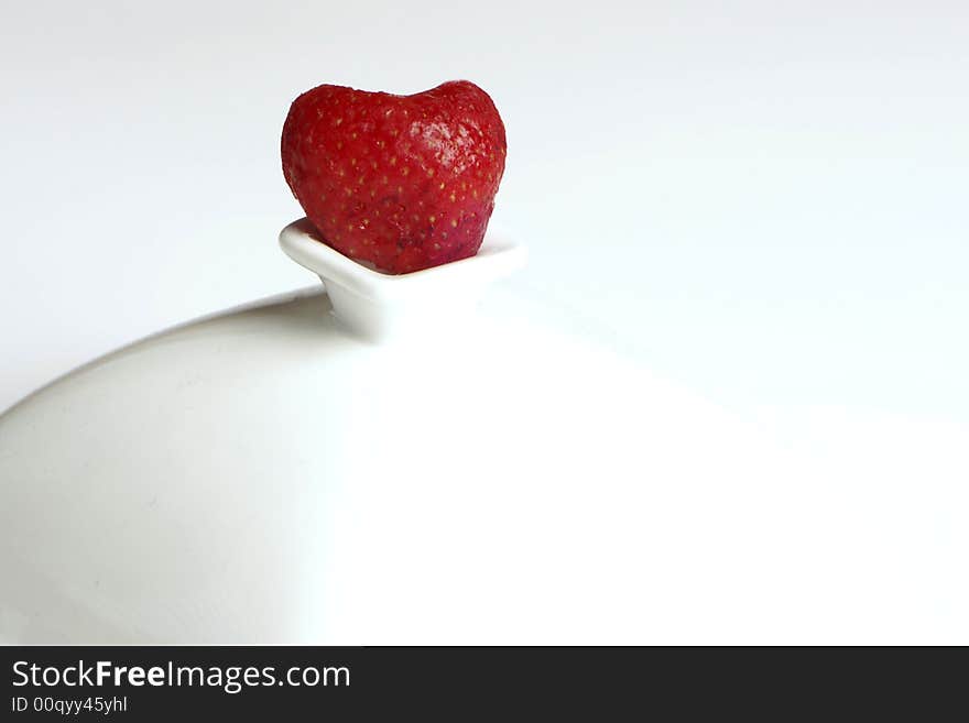 Heart shaped strawberry sitting on perch. Heart shaped strawberry sitting on perch