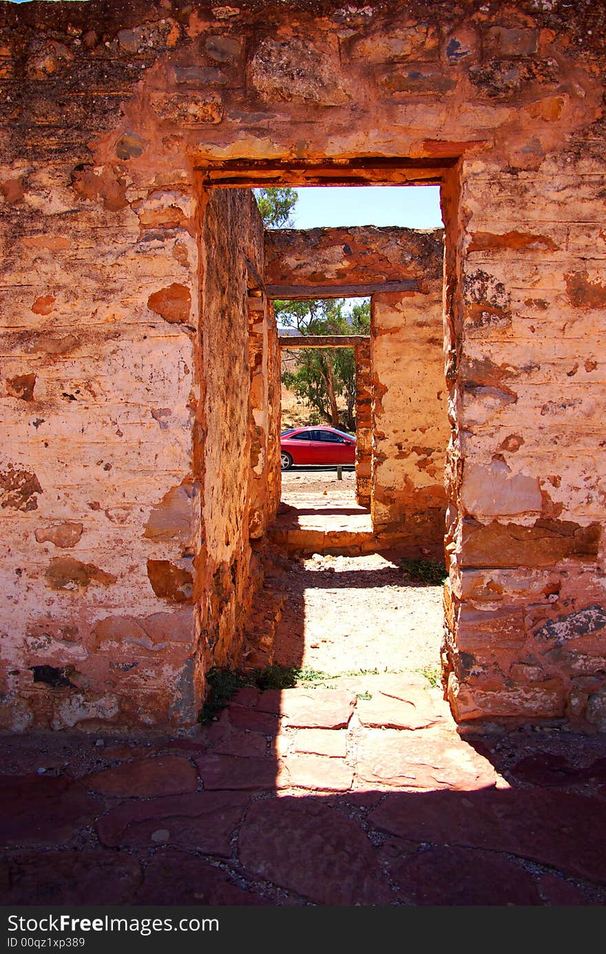 Kanyaka Ruins near Hawker featuring several doorways in a ruined outback building, looking through to a modern coupe car (Flinders Ranges, South Australia).