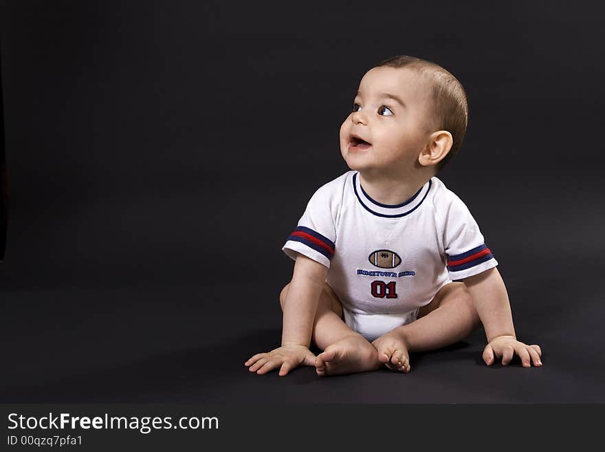 Curious happy baby on black surface