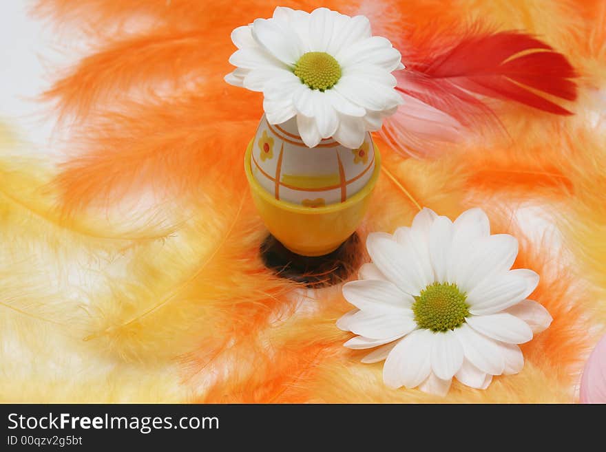 Easter egg with flower on yellow and orange feathers.