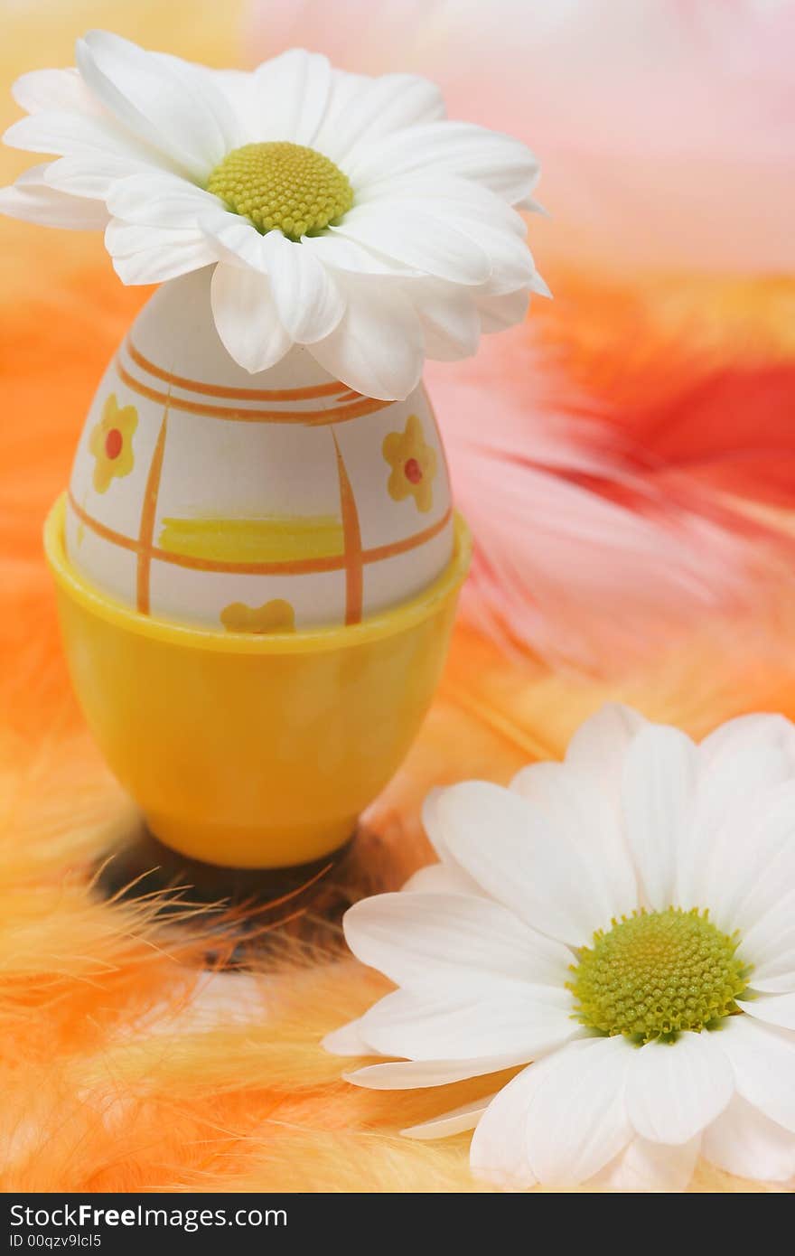 Easter egg with flowers and pink and orange feathers.