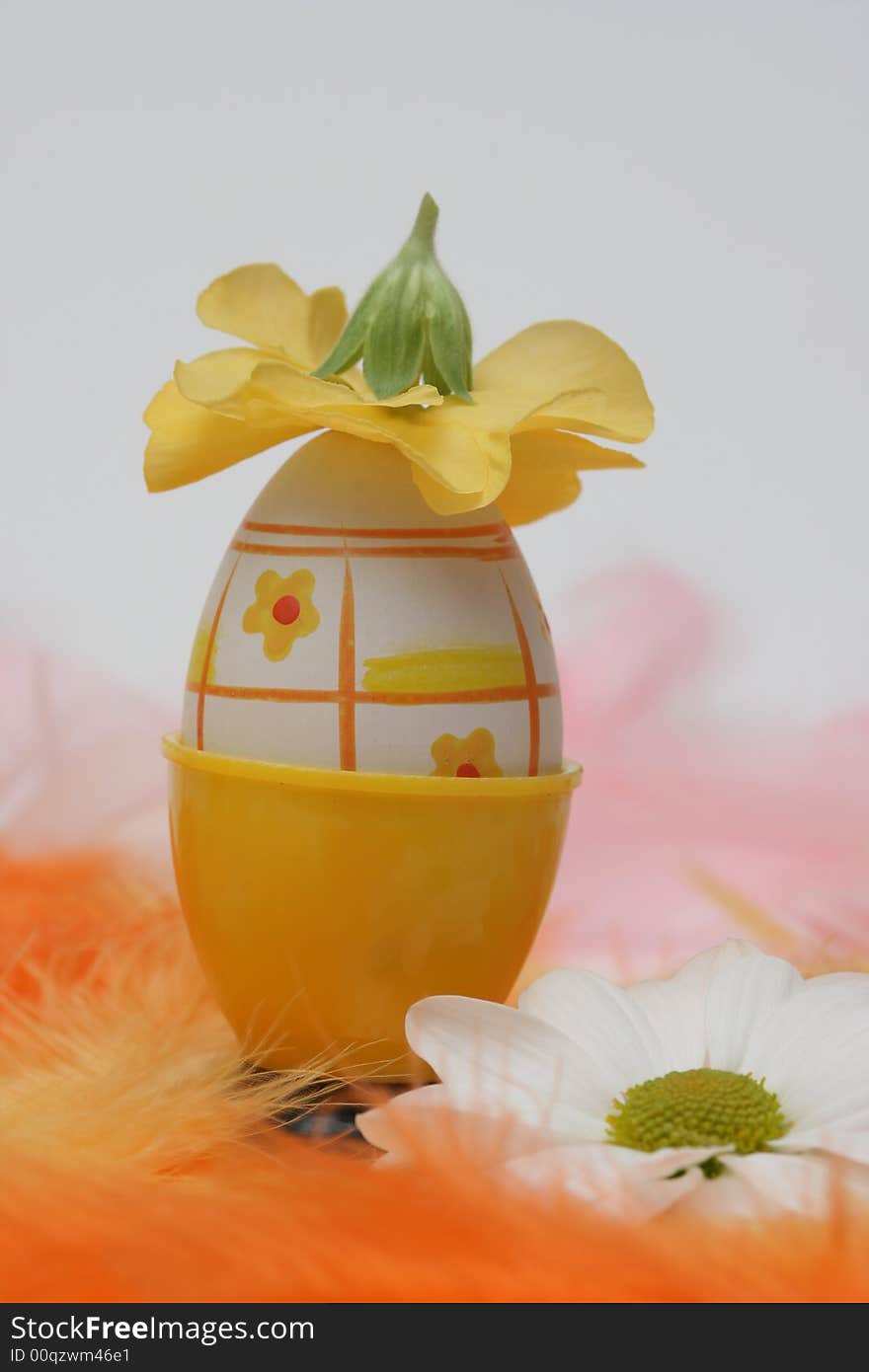 Easter egg with flower on yellow and orange feathers.