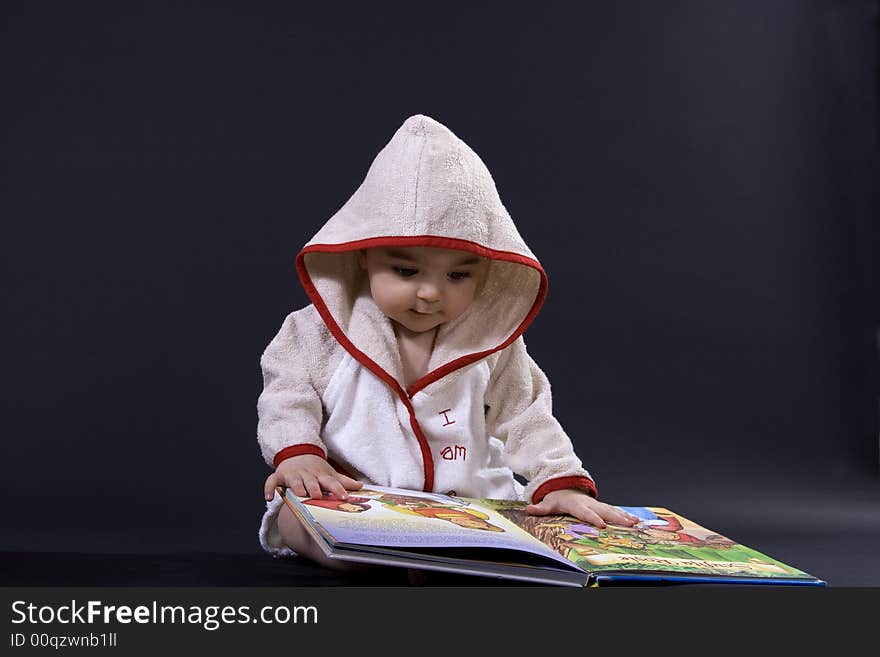 Curious happy baby on black surface reading a story. Curious happy baby on black surface reading a story