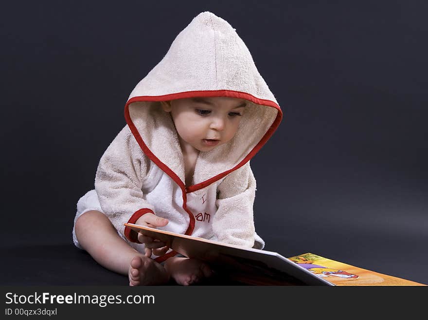 Curious happy baby on black surface reading a story. Curious happy baby on black surface reading a story