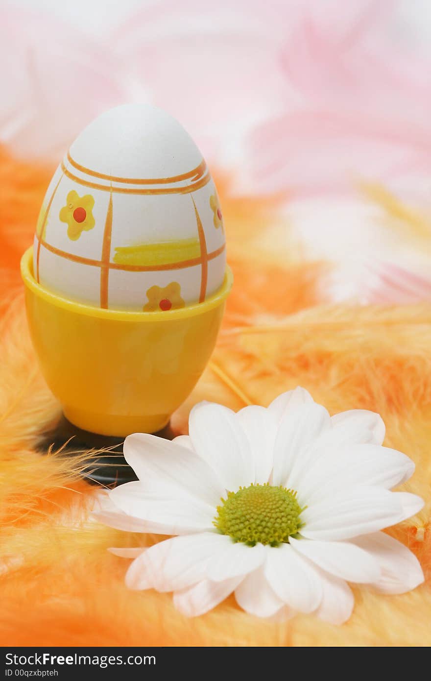 Easter egg with white flowers and pink and orange feathers.