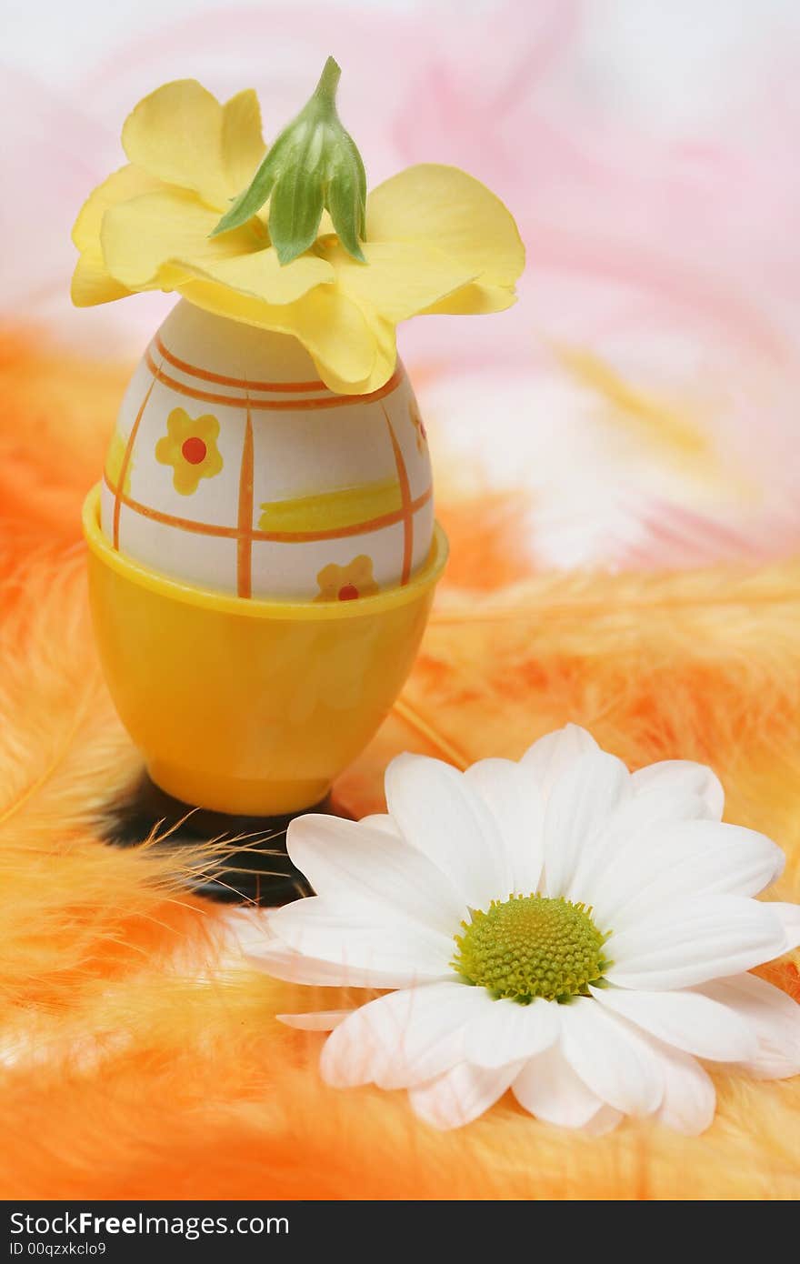 Easter egg with flowers and pink and orange feathers.