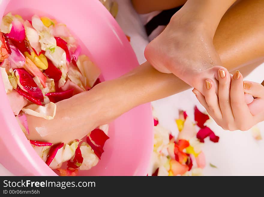 Beautiful young woman legs in water with petals. Beautiful young woman legs in water with petals