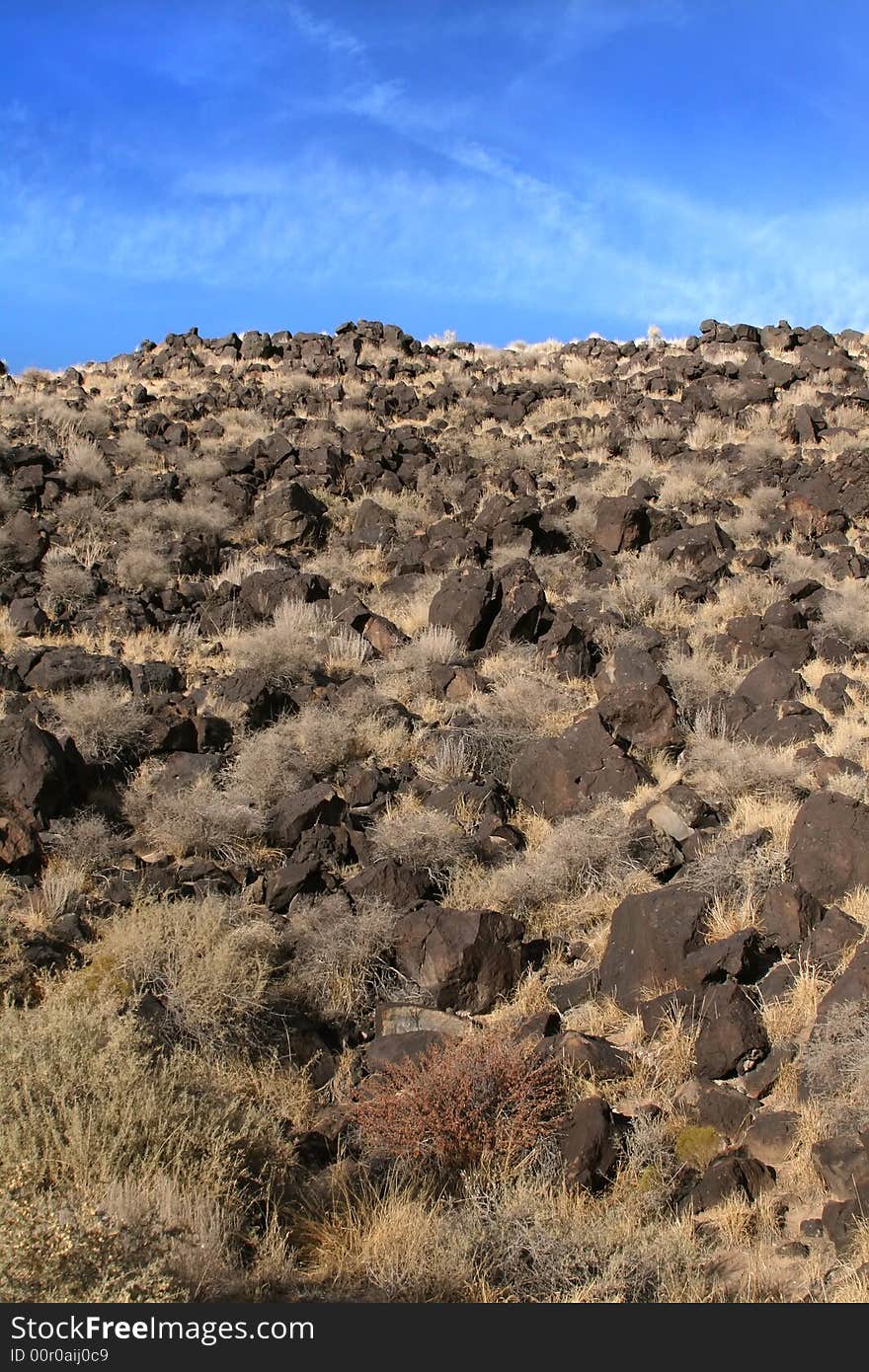 A rocky hill leading into a cloudy blue sky