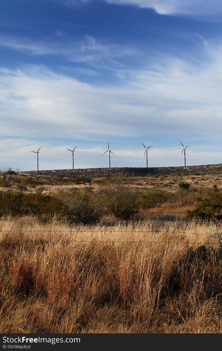 A grouping of wind turbines in a grassland setting