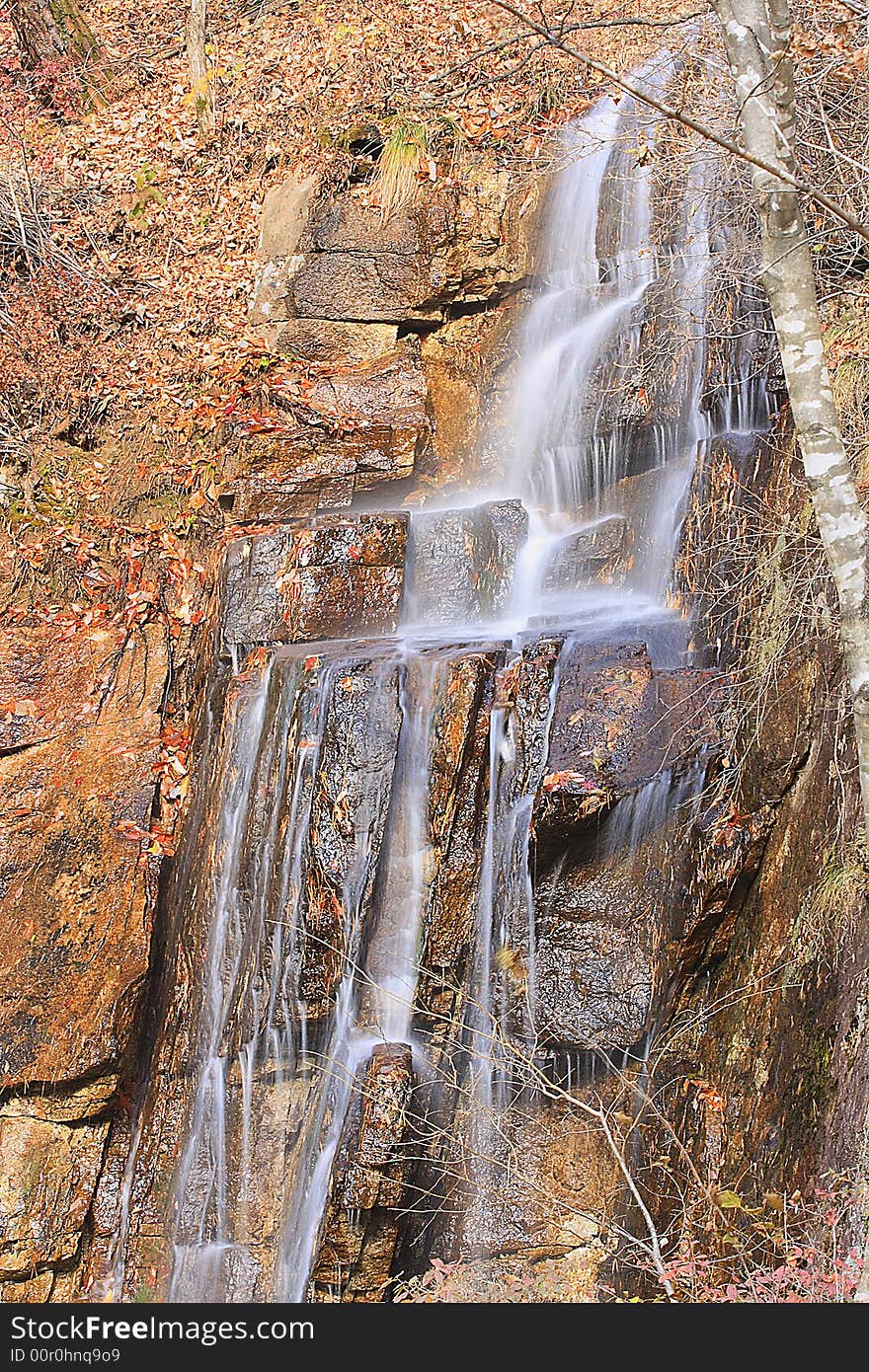 River flows down softly from a mountain. Waterfall