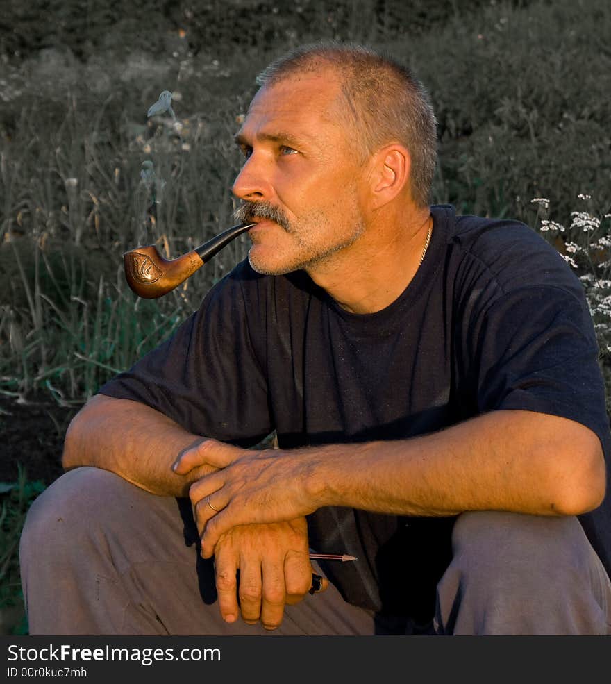 The man smoking a tube, shined with beams of the evening sun. The man smoking a tube, shined with beams of the evening sun