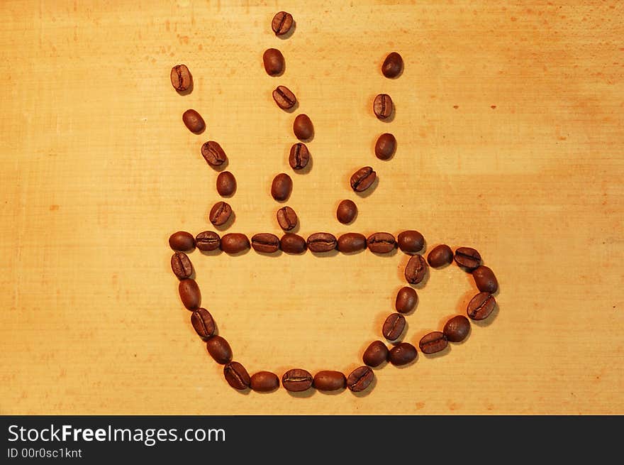 Cup of hot flavoured coffee spreaded out of coffee beans