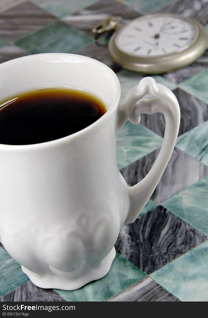 Cup of coffee with an antique pocket watch in the background. Cup of coffee with an antique pocket watch in the background.